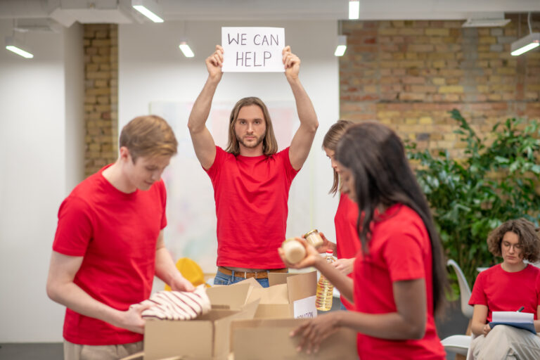 Sorting center. Young volunteers in red tshirts distributing donations in a sorting center